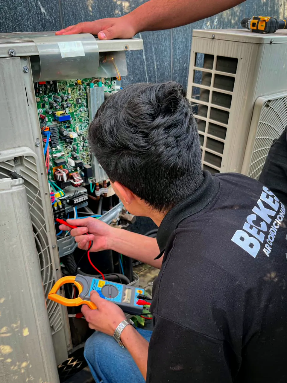 Técnico da Beckes medindo a corrente da placa eletrônica de uma condensadora com alicate amperímetro